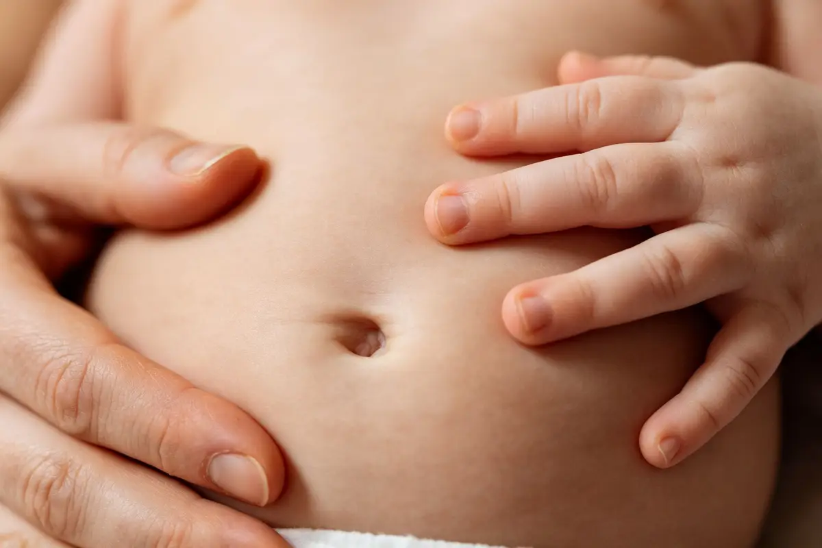 Close up of baby belly with hands gently rubbing for gas relief