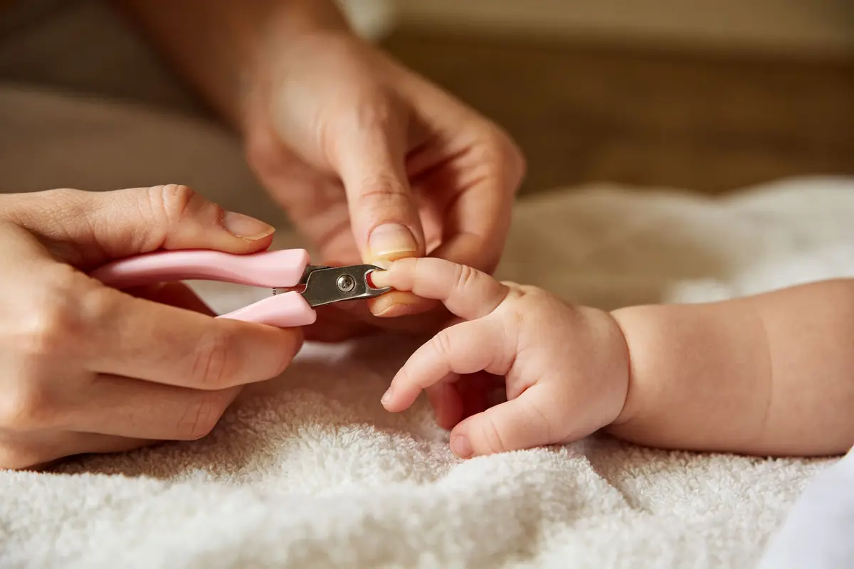 Mother carefully trimming baby fingernails with baby nail clippers close up