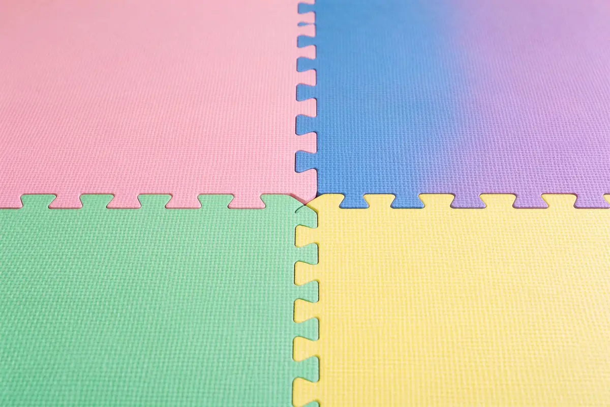 Close-up of interlocking foam baby play mat tiles in pastel pink, blue, green, and yellow