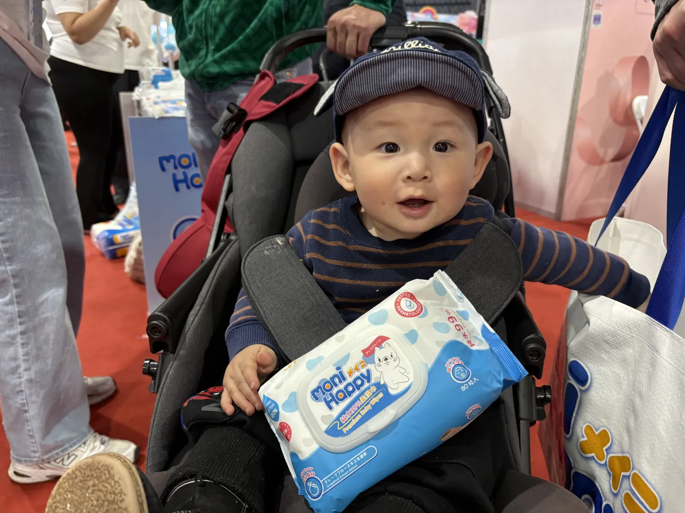 Toddler holding a pack of Moni Happy baby wipes at the expo in Mongolia