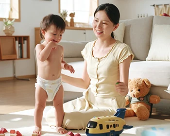 Mother and toddler playing at home, the toddler wearing a Moni Happy diaper